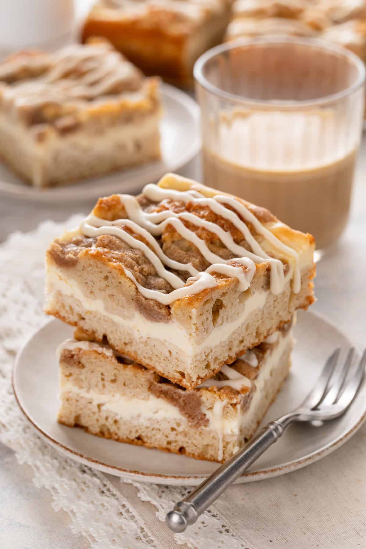 Two slices of cream cheese coffee cake stacked on a white plate.