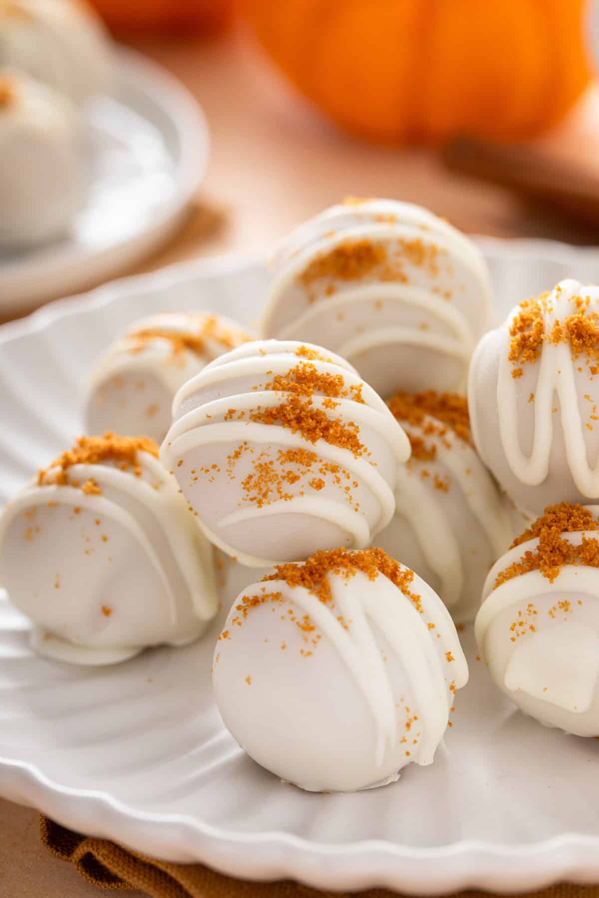 Pumpkin cheesecake balls stacked on a white platter.