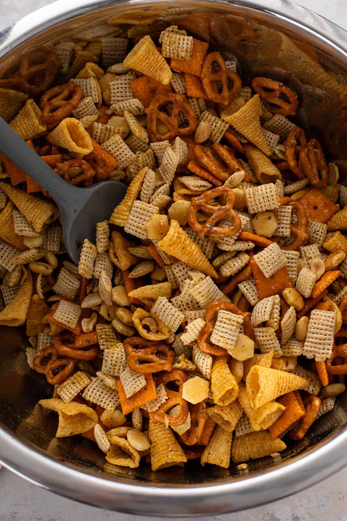 Cereal mixture stirred with seasonings for ranch chex mix.