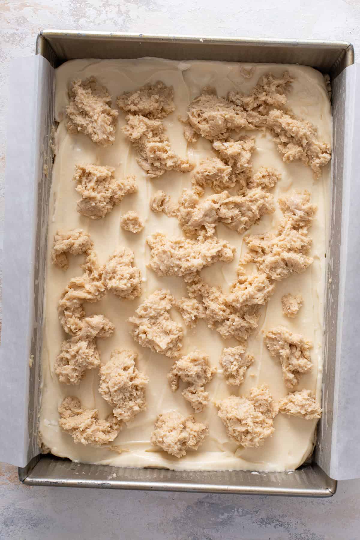 Top layer of batter for cream cheese coffee cake spooned over cream cheese filling layer.