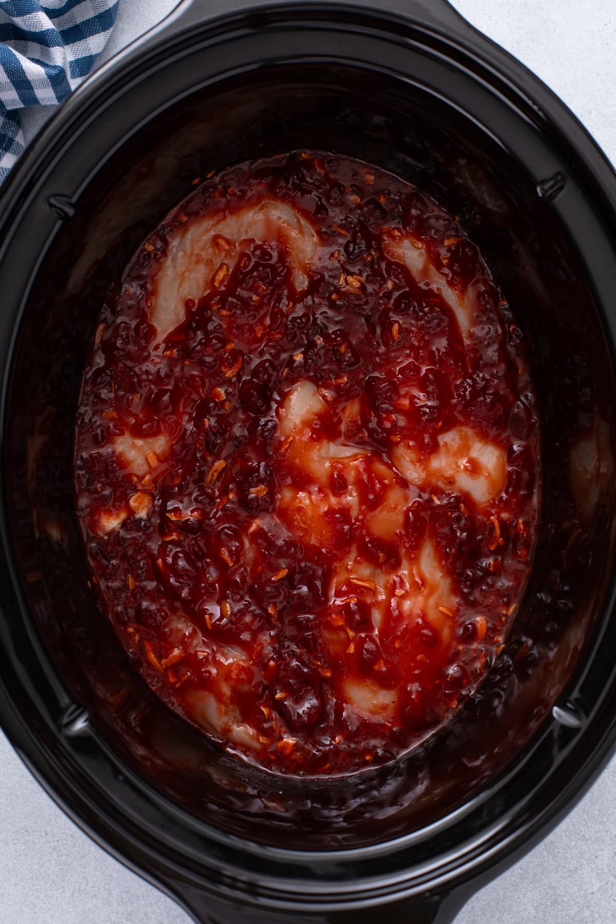 Chicken added to sauce in a slow cooker.