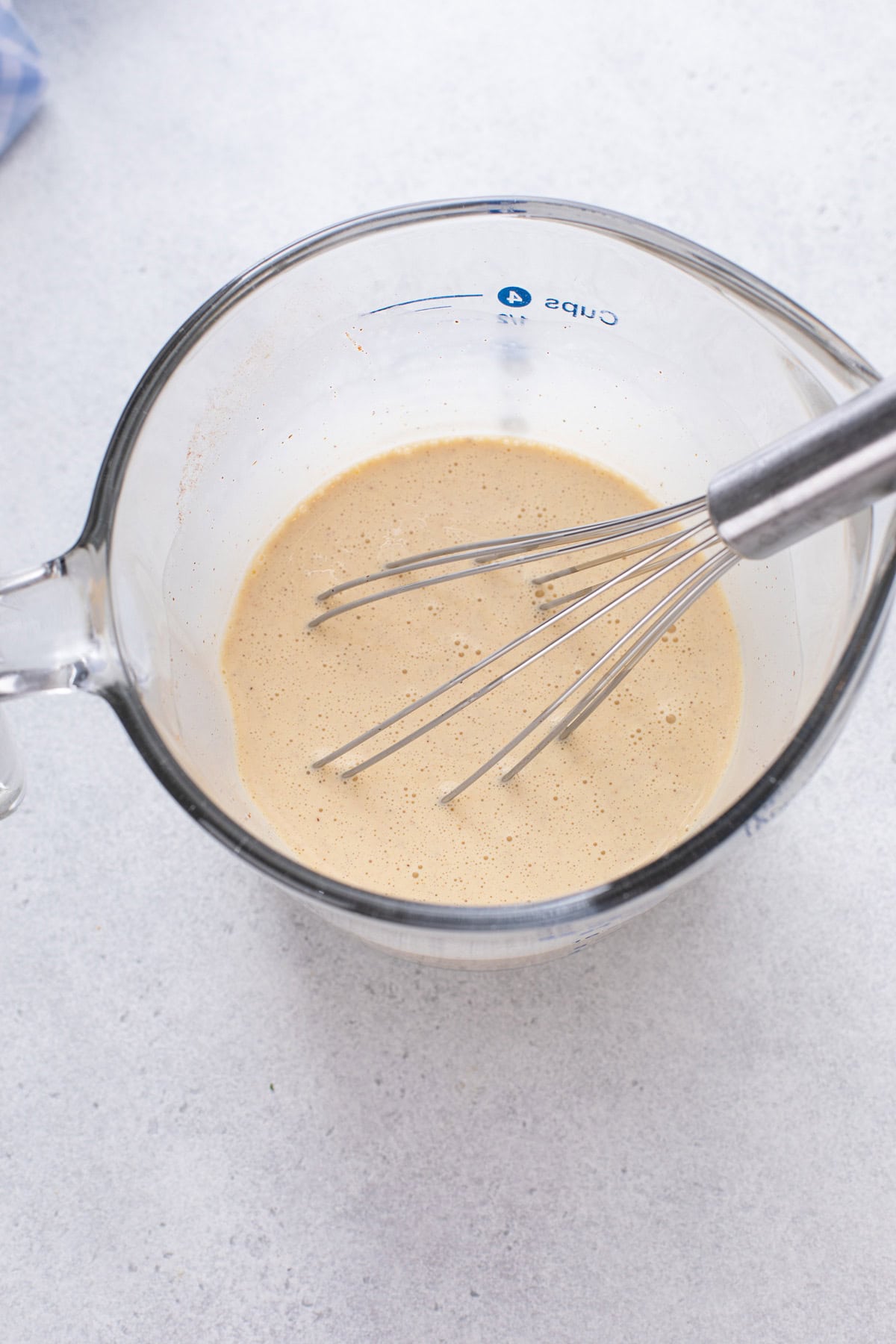 Custard for cinnamon roll casserole whisked in a measuring cup.