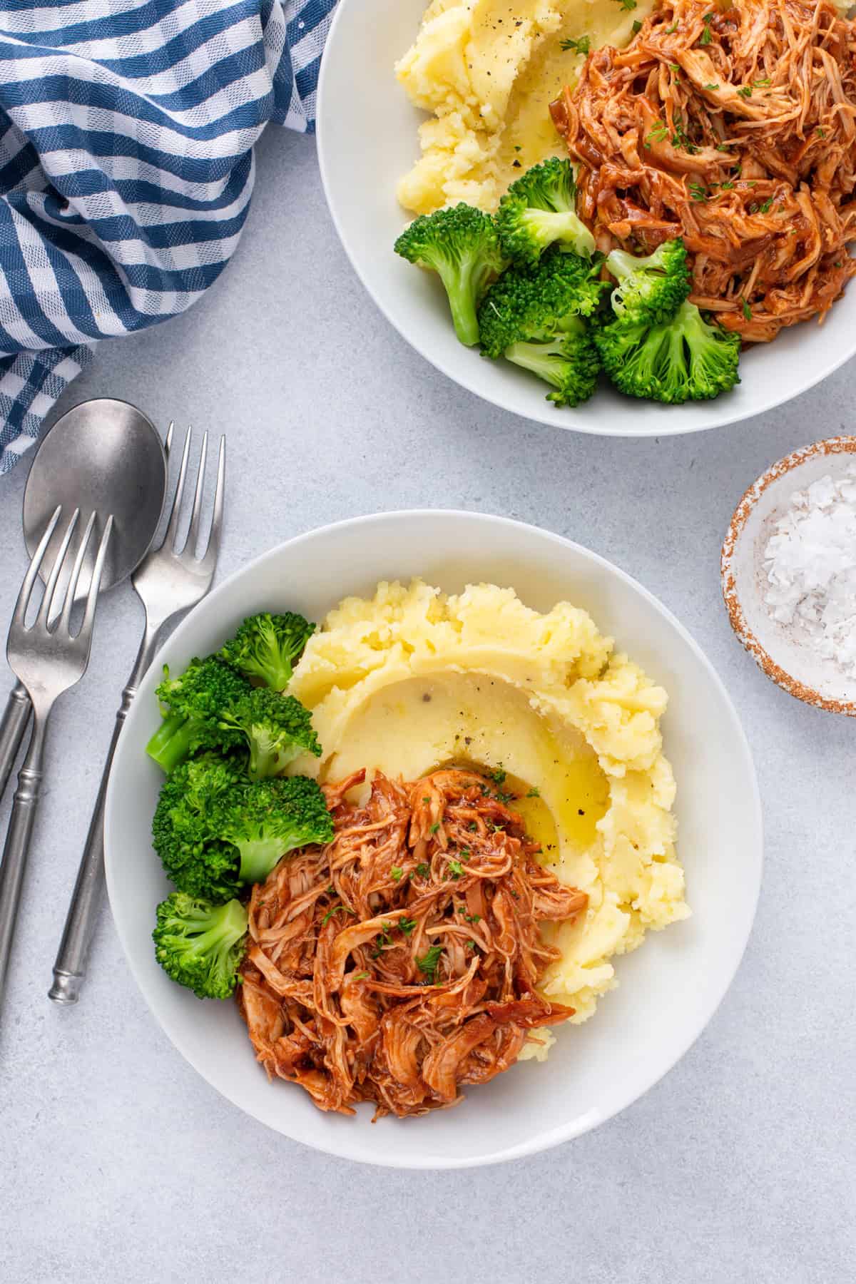 Overhead view of two plates of cranberry chicken with mashed potatoes and broccoli.