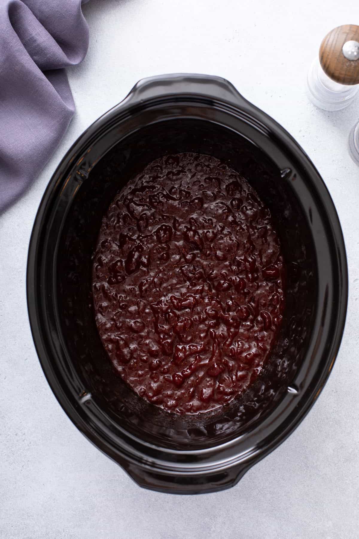 Sauce for cranberry meatballs mixed in the crock of a slow cooker.