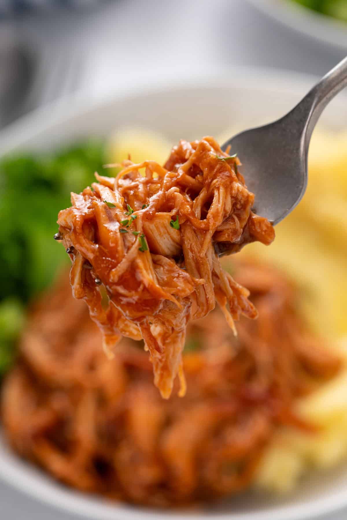 Fork holding up a bite of cranberry chicken.
