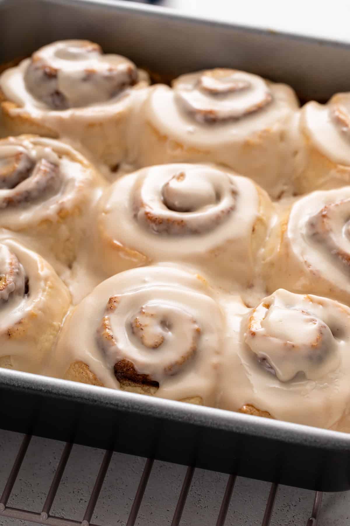 Icing on top of biscuit cinnamon rolls in a baking pan.