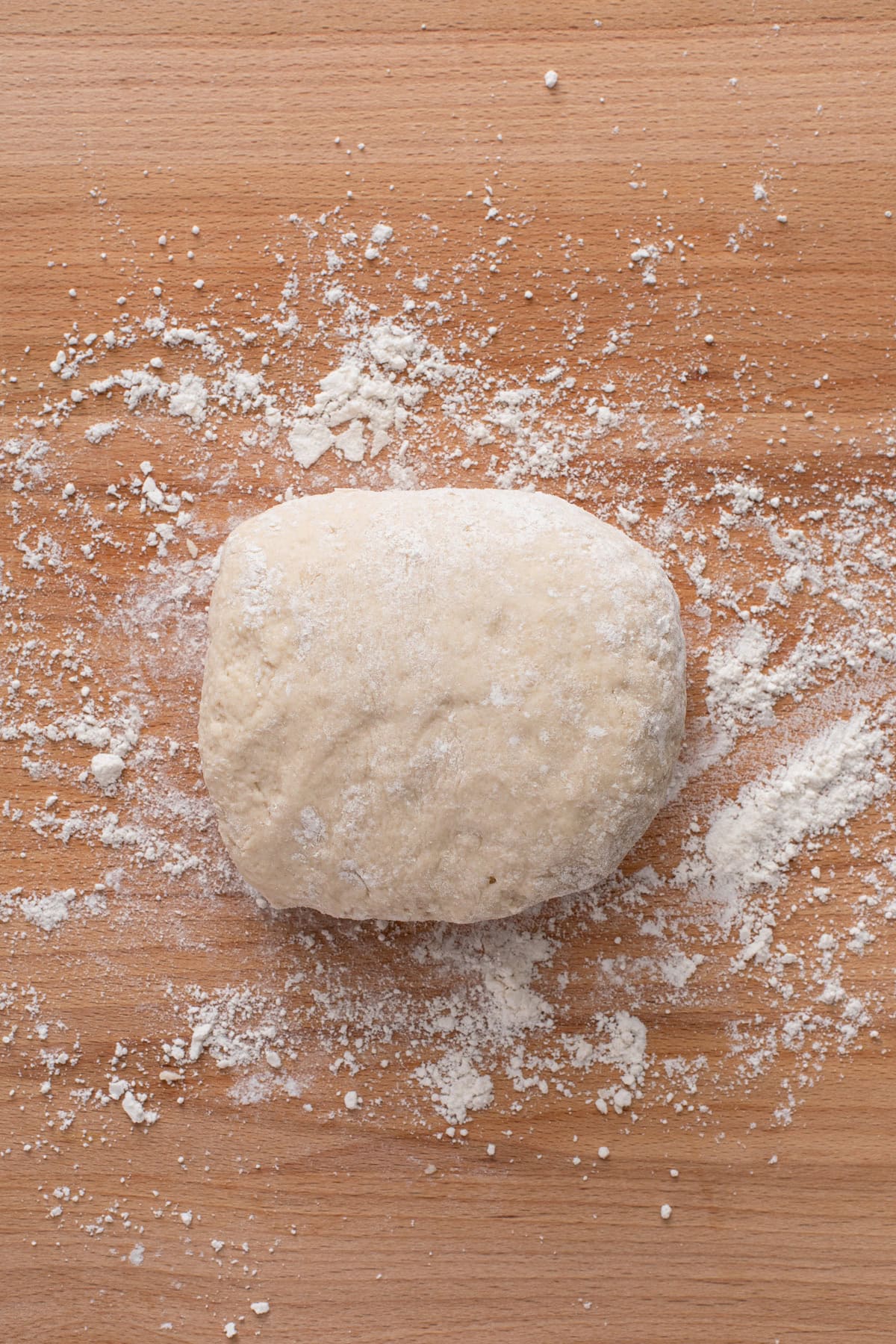 Biscuit dough kneaded on a wooden board.