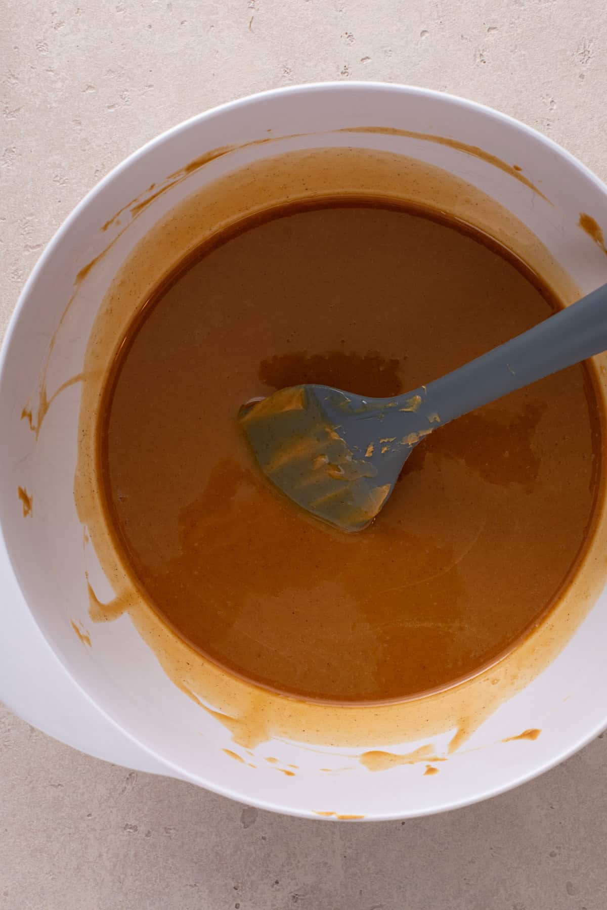 Melted peanut butter mixture in a white mixing bowl.