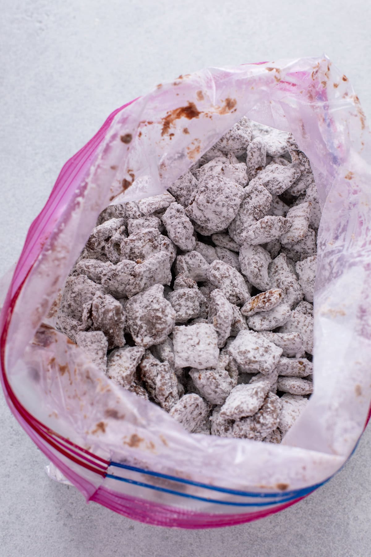 Chocolate-coated cereal dusted with powdered sugar in a zip-top bag.