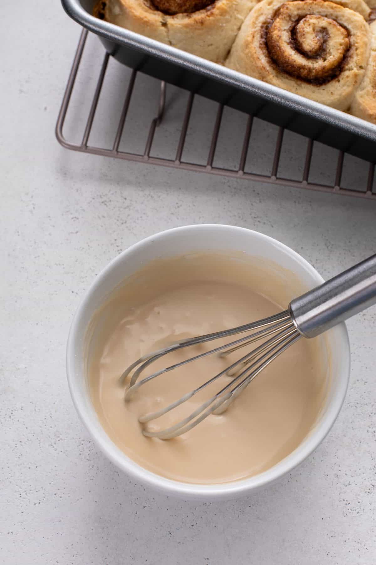 Vanilla icing for biscuit cinnamon rolls whisked in a small bowl.