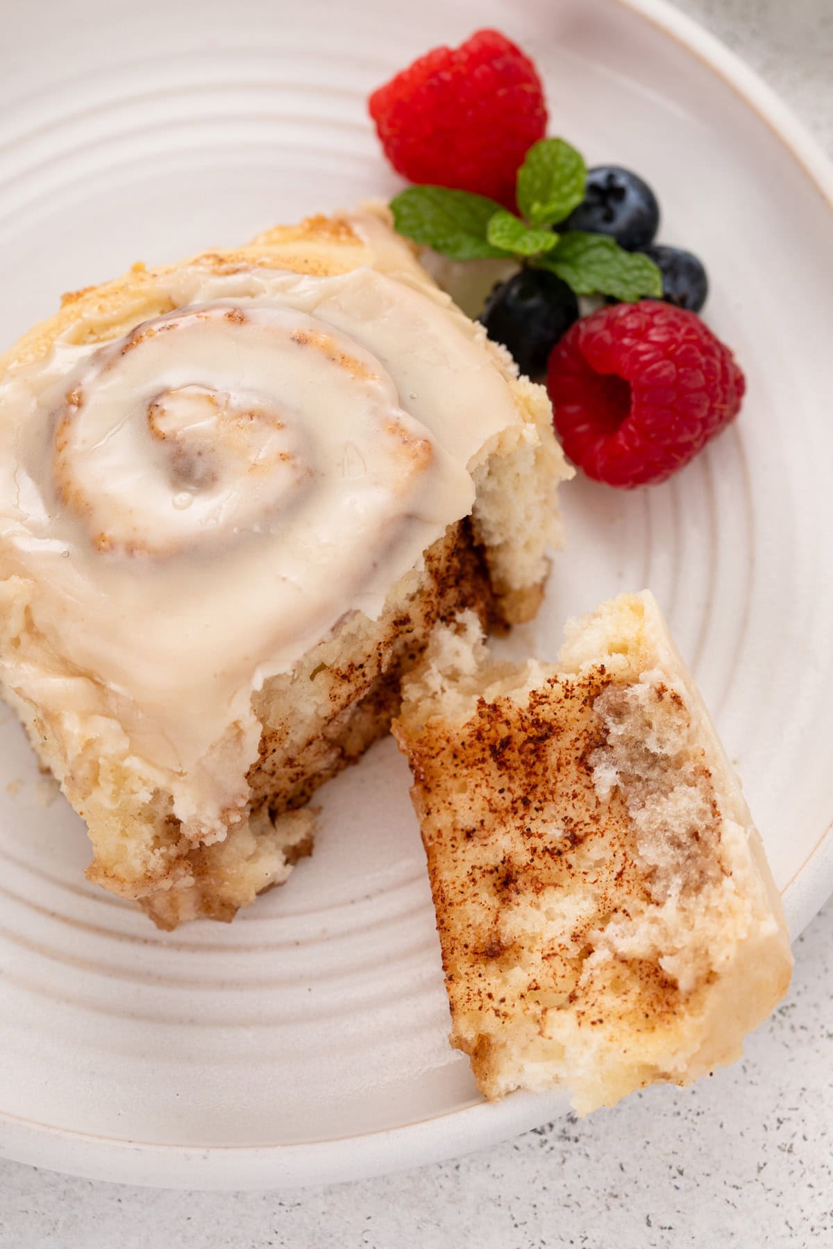 Plated biscuit cinnamon roll with a piece torn from the edge.