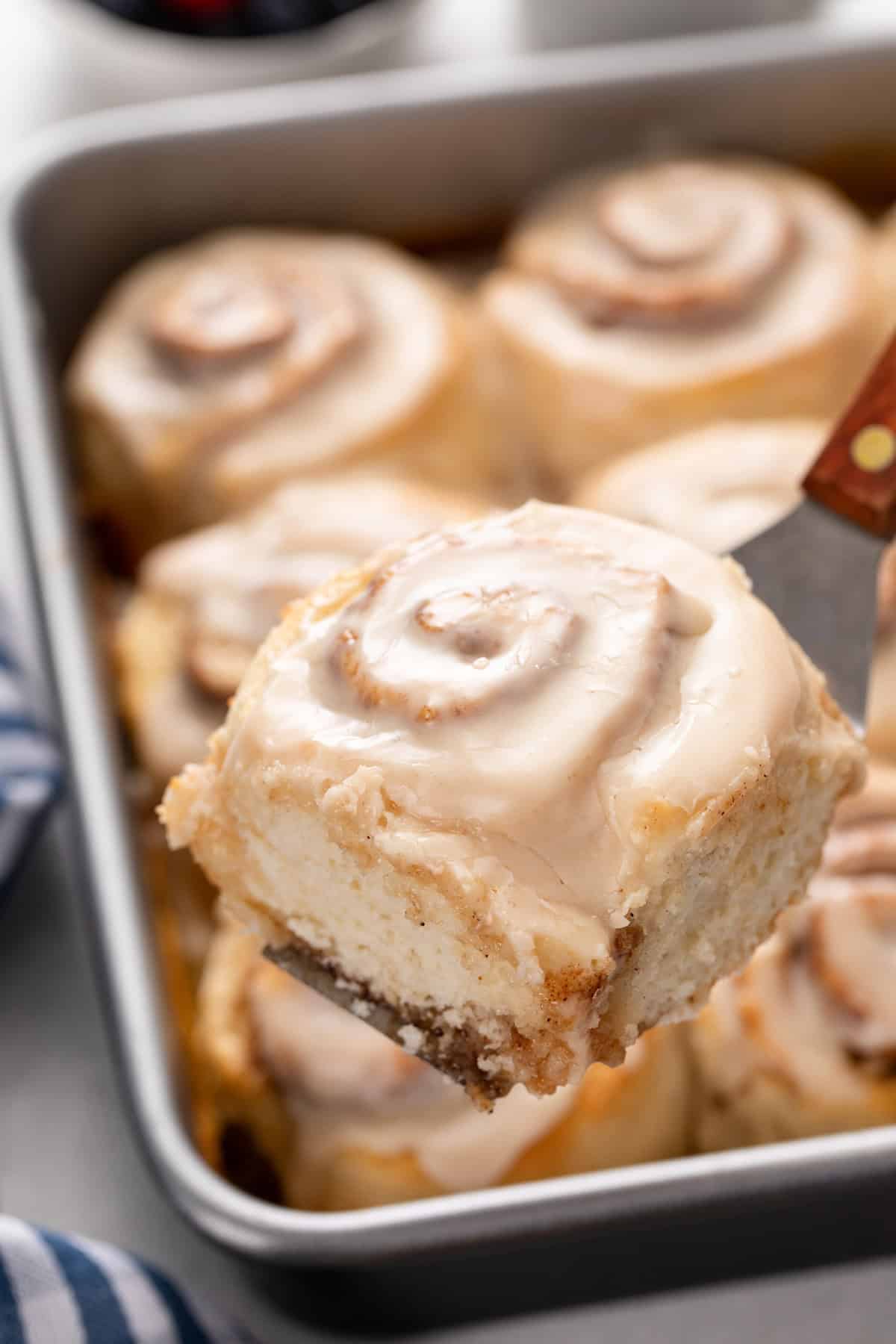 Cake server lifting up a biscuit cinnamon roll.