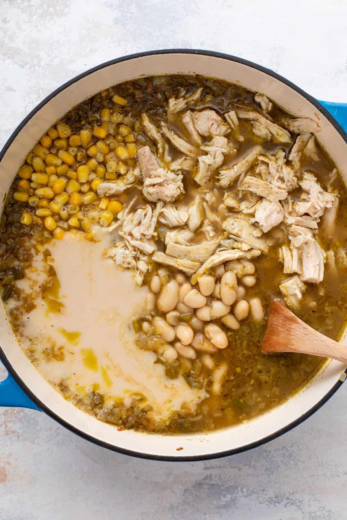 White beans, chicken, and corn added to a pot of white chili.