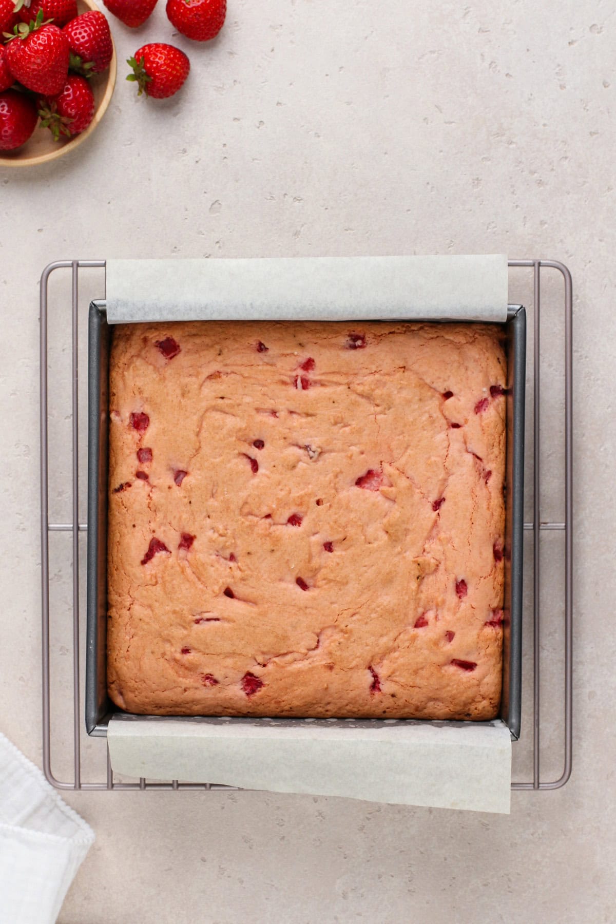 Baked pan of strawberry brownies cooling on a wire rack.