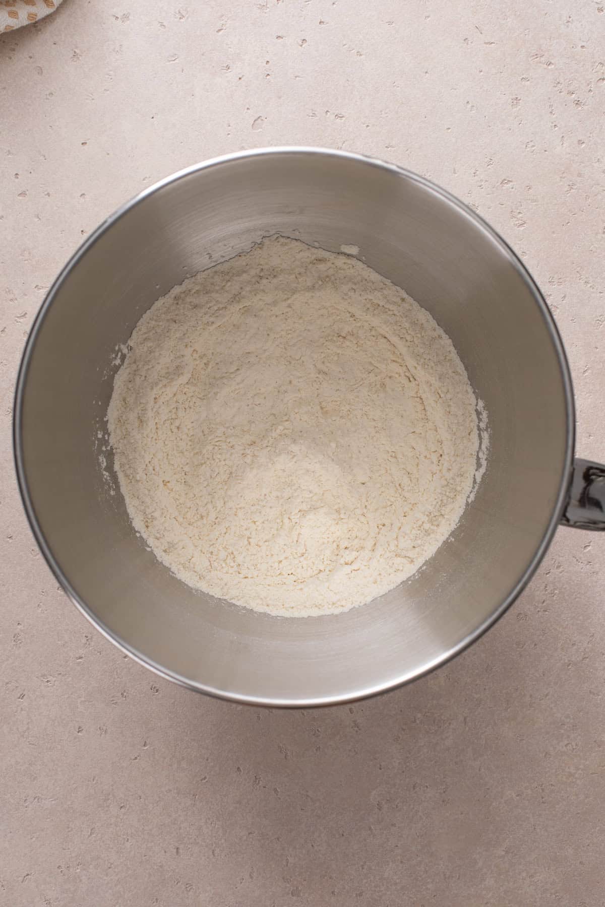 Dry ingredients for potato bread added to a metal mixing bowl.