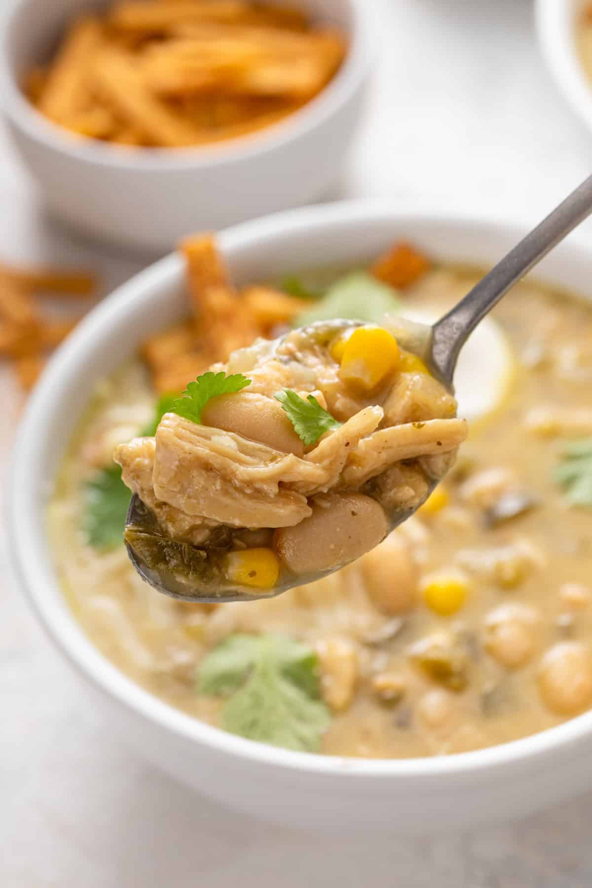 Spoonful of white chicken chili being held up to the camera.
