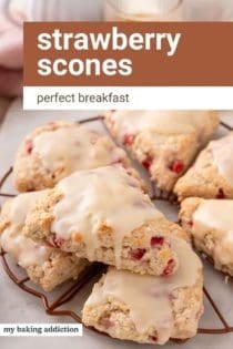 Strawberry scones stacked on a wire rack. A cup of coffee is seen in the background. Text overlay includes recipe name.