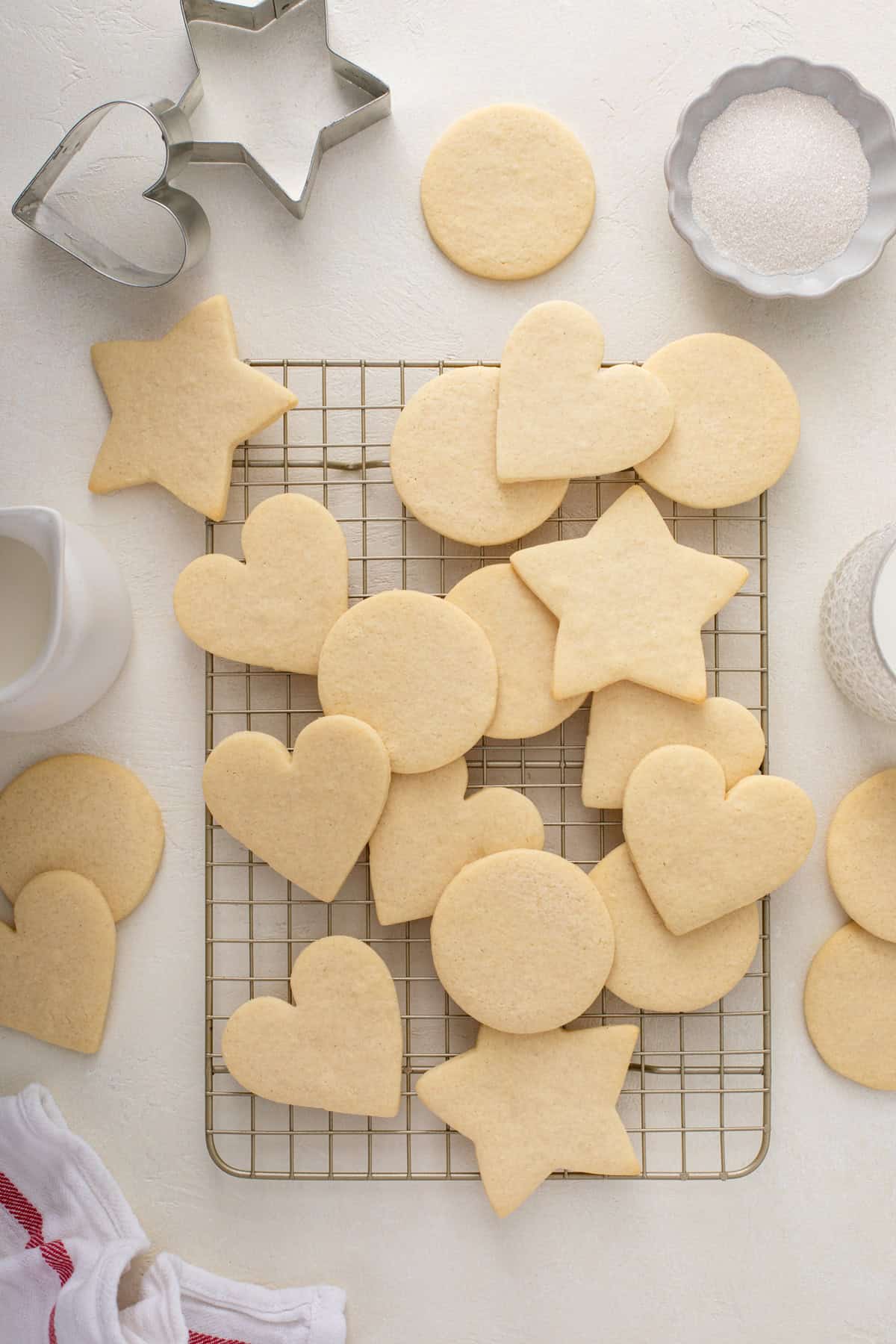 Undecorated no-spread sugar cookies in assorted shapes cooling on a wire rack on a countertop.