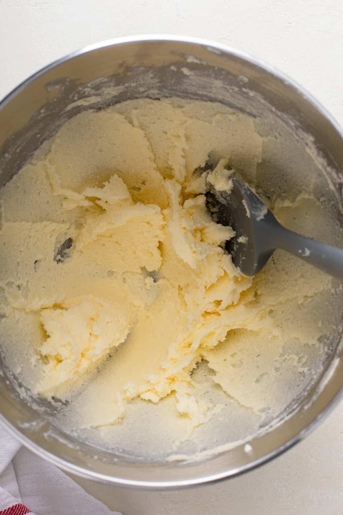 Butter and sugar creamed together in a metal mixing bowl.