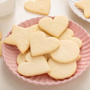 Several no-spread cut-out sugar cookies arranged on a pink plate.