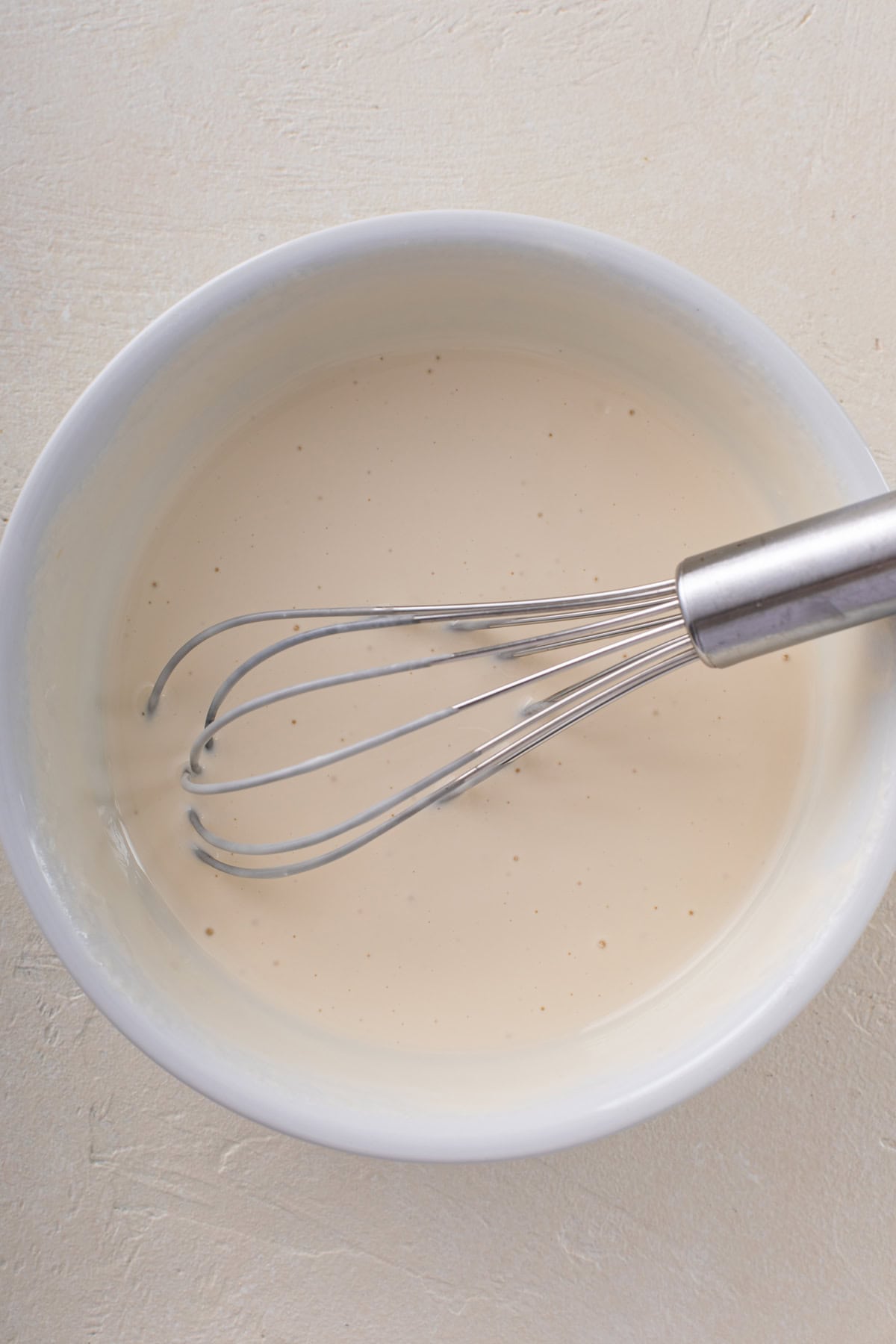 Wet ingredients for strawberry scones whisked in a white bowl.