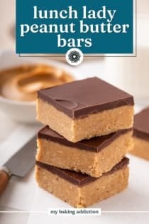 Three lunch lady peanut butter bars stacked on a piece of parchment with a glass of milk and bowl of peanut butter in the background. Text overlay includes recipe name.