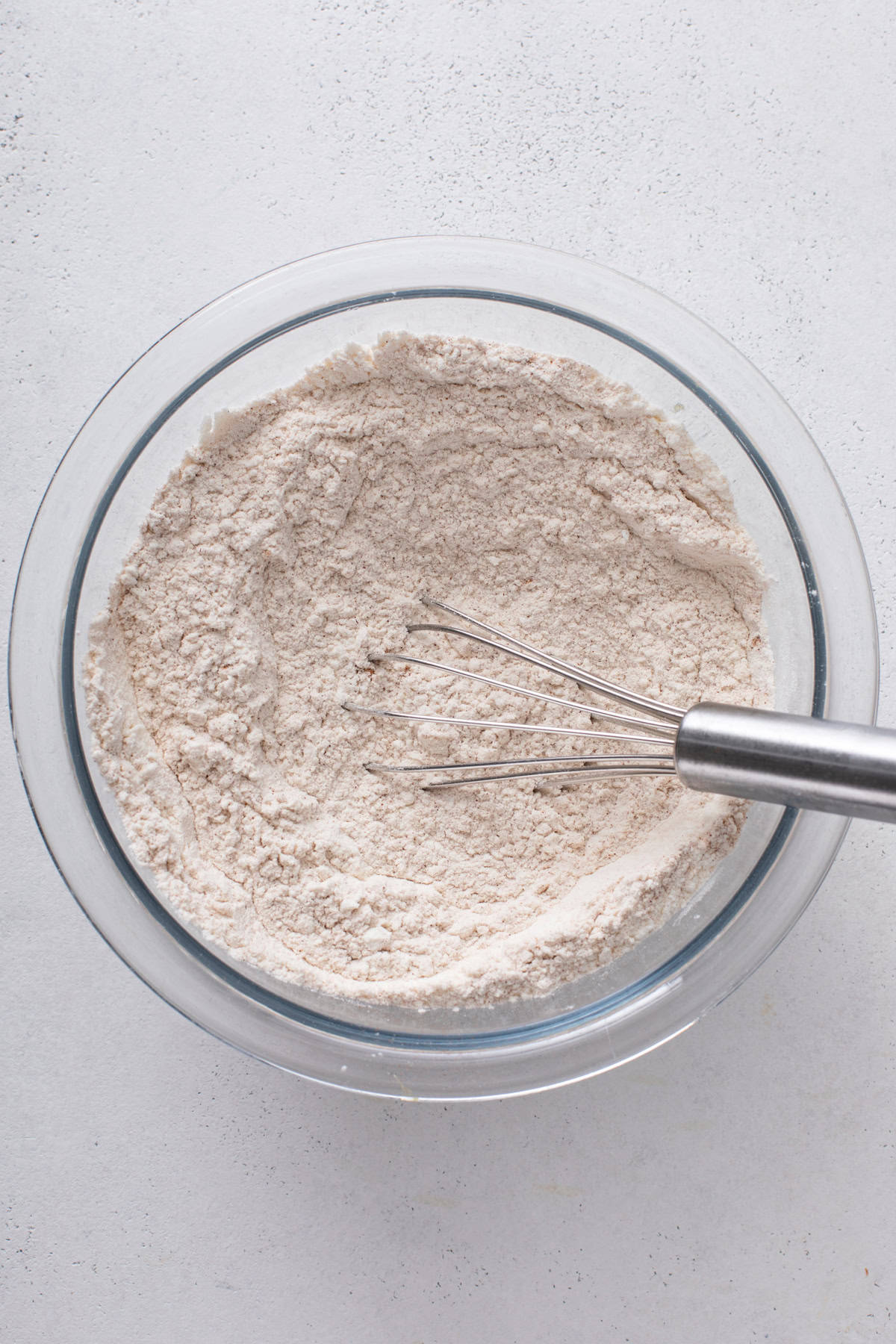 Dry ingredients for carrot cake cookies whisked together in a glass bowl.