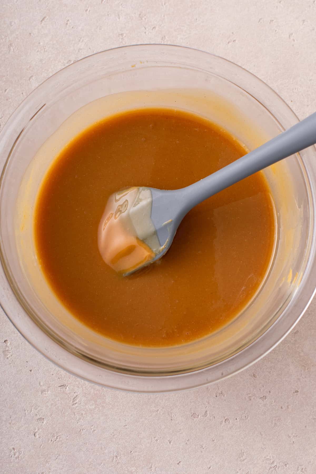 Butter and peanut butter melted together in a glass bowl.