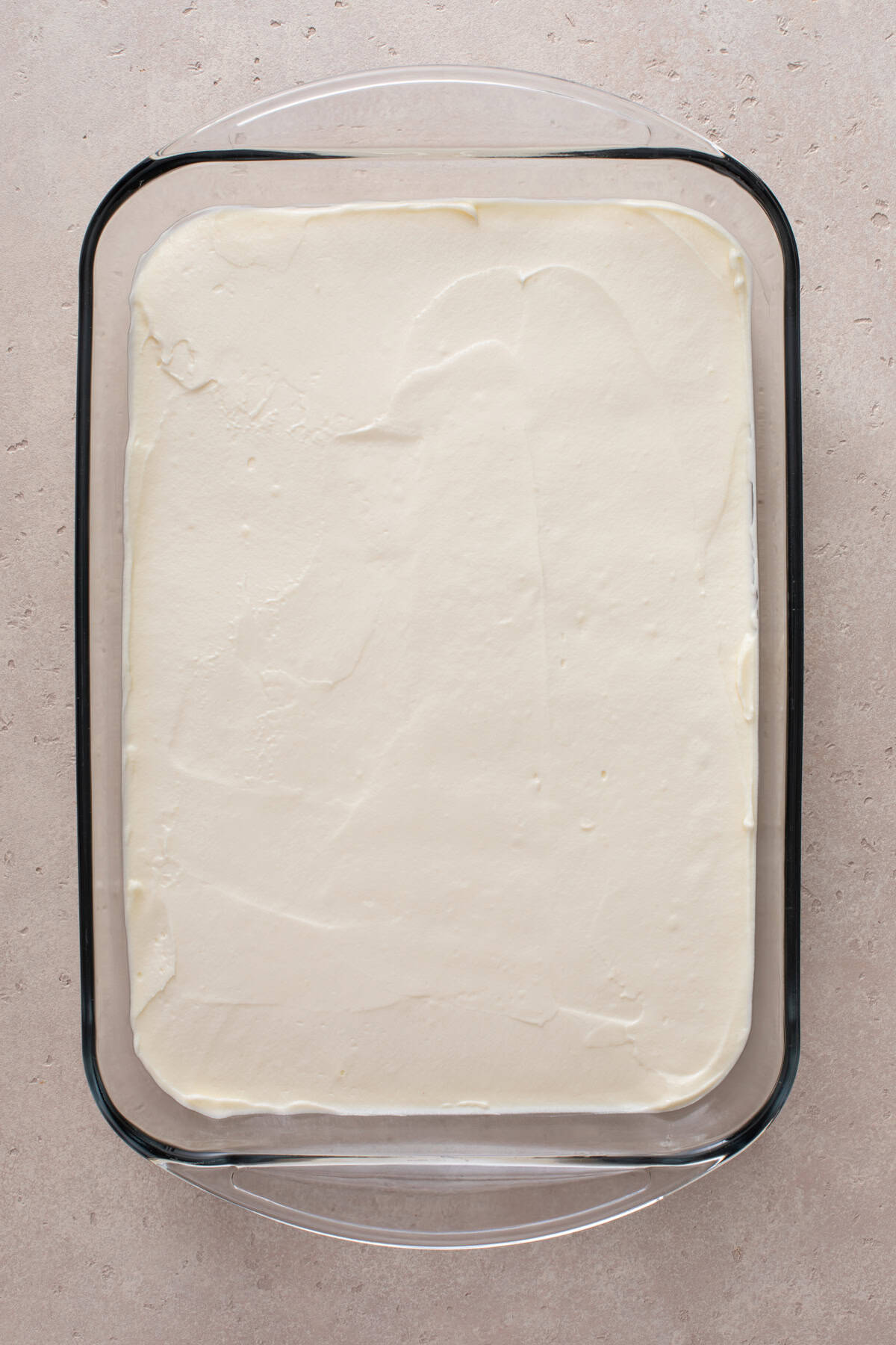 Cream cheese mixture spread over a pretzel crust in a glass pan.