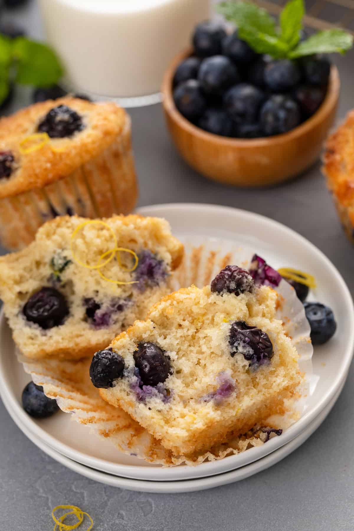 Halved lemon blueberry muffin laying on a white plate.