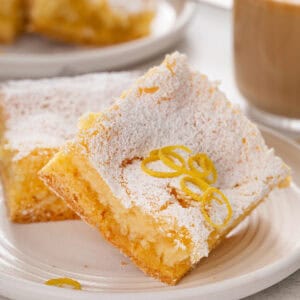 Close up of 2 slices of lemon gooey butter cake on a white plate.