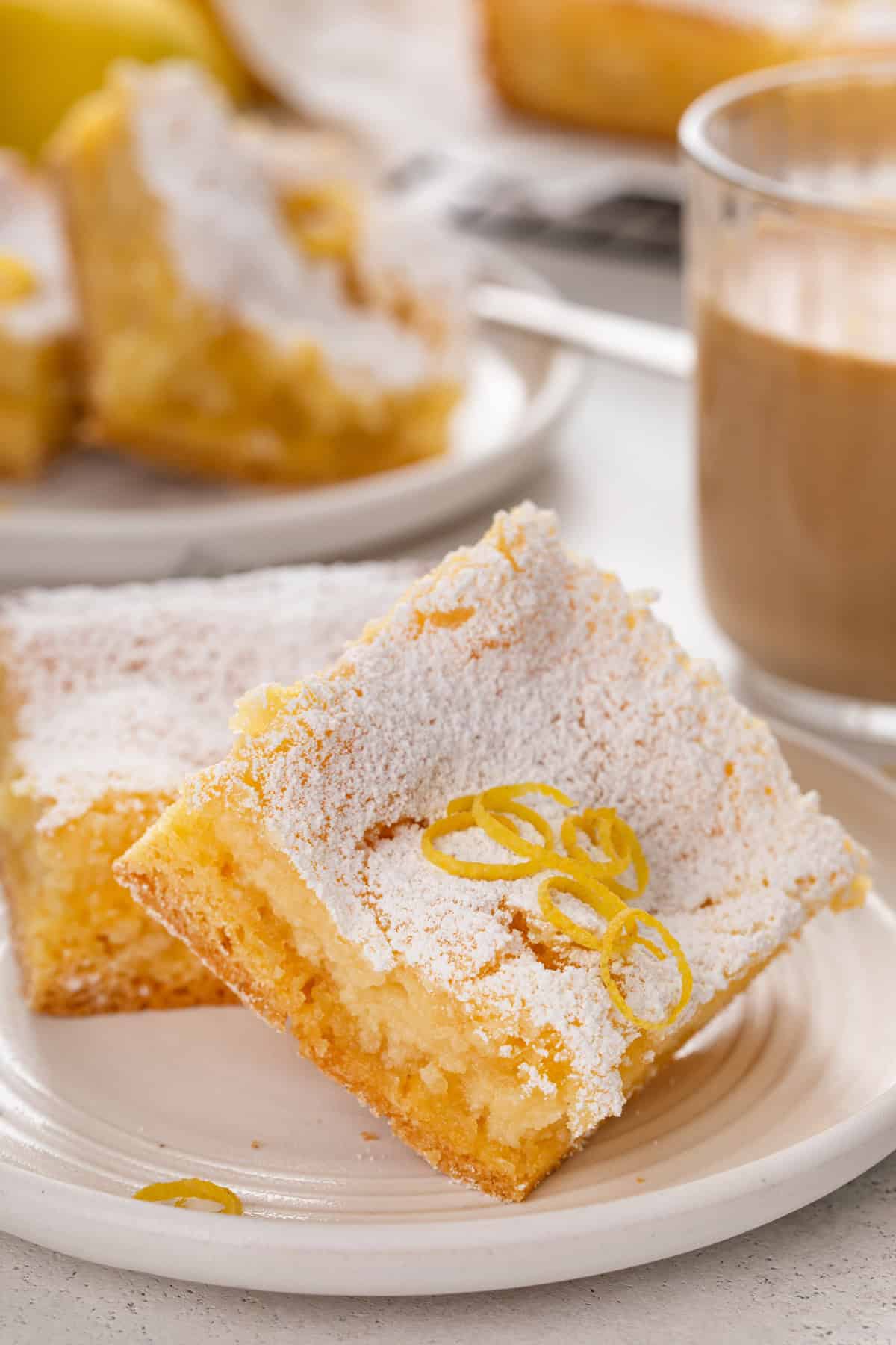 Two slices of lemon gooey butter cake arranged on a white plate.